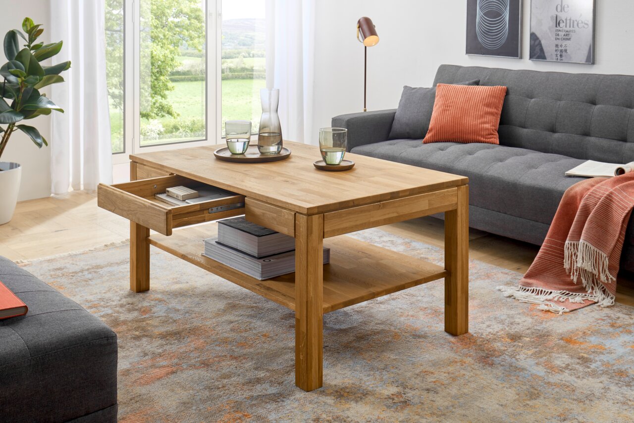 Zurbrüggen Couchtisch SALEM Holz-Couchtisch mit Schublade und Ablagefläche, seitliche Perspektive, in modernem Wohnzimmer mit grauem Sofa und orangenem Kissen.