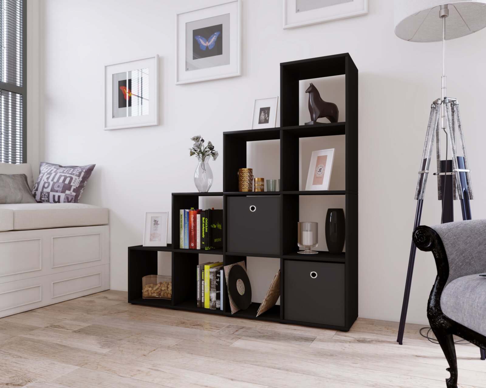 Modernes schwarzes Stufenregal mit offenen Fächern und zwei Boxeinsätzen, dekoriert mit Büchern und Vasen, in Wohnzimmer-Umgebung; perspektivische Ansicht schräg von vorn.
