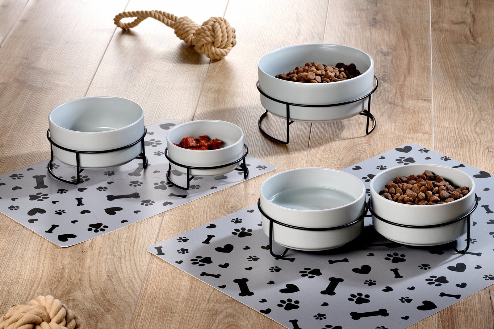 2-delige voerbakset, 400 ml, van keramiek met een zwarte metalen standaard, op een decoratieve onderlegger met een patroon van pootafdrukken en botten, zijaanzicht