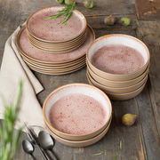Geschirrset Terra 18-tlg. mit rosa gemusterten Tellern und Schalen, auf einem rustikalen Holztisch arrangiert, von oben fotografiert.
