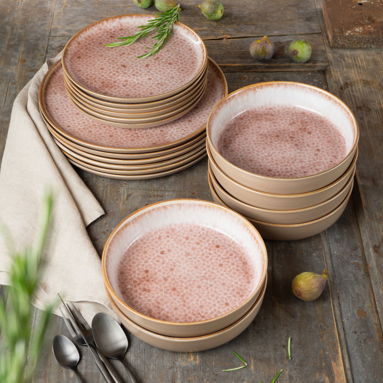 Geschirrset Terra 18-tlg. mit rosa gemusterten Tellern und Schalen, auf einem rustikalen Holztisch arrangiert, von oben fotografiert.