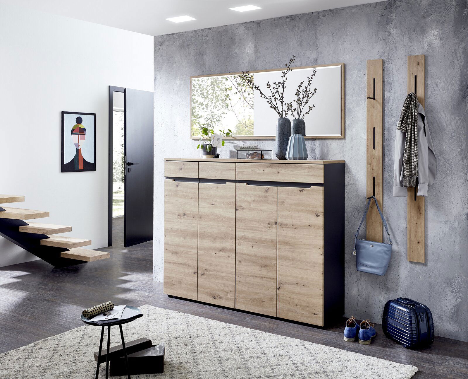 Moderner Eingangsbereich mit einem XL-Schuh- und Garderobenschrank in Holzoptik, flankiert von zwei schmalen Garderobenpaneelen. Perspektive von vorne.