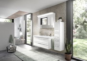 Moderner Badblock in einem hellen Badezimmer mit großen Fenstern, bestehend aus einem weißen Waschtisch mit Schubladen und einem hohen, schmalen Schrank. Perspektive von schräg vorne.
