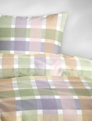 Close-up vanuit schuin vooraanzicht van een dekbedovertrek met bijpassend kussensloop en een groot ruitpatroon in zachte pastelkleuren zoals groen, lila, roze en oranje.