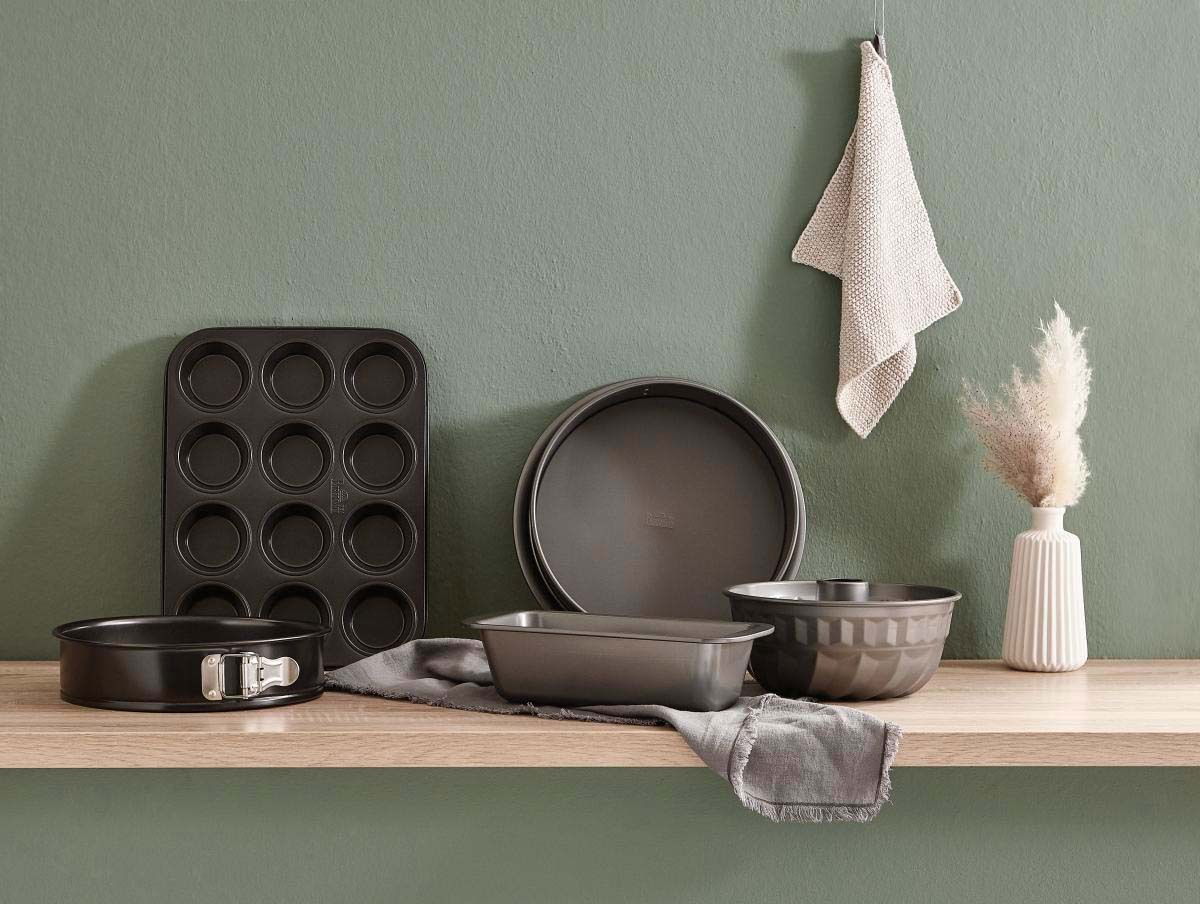 Eine Springform mit 26 cm Durchmesser, präsentiert auf einem Holzregal in einer modernen Küchenszene, umgeben von weiteren Backformen und Küchenaccessoires.