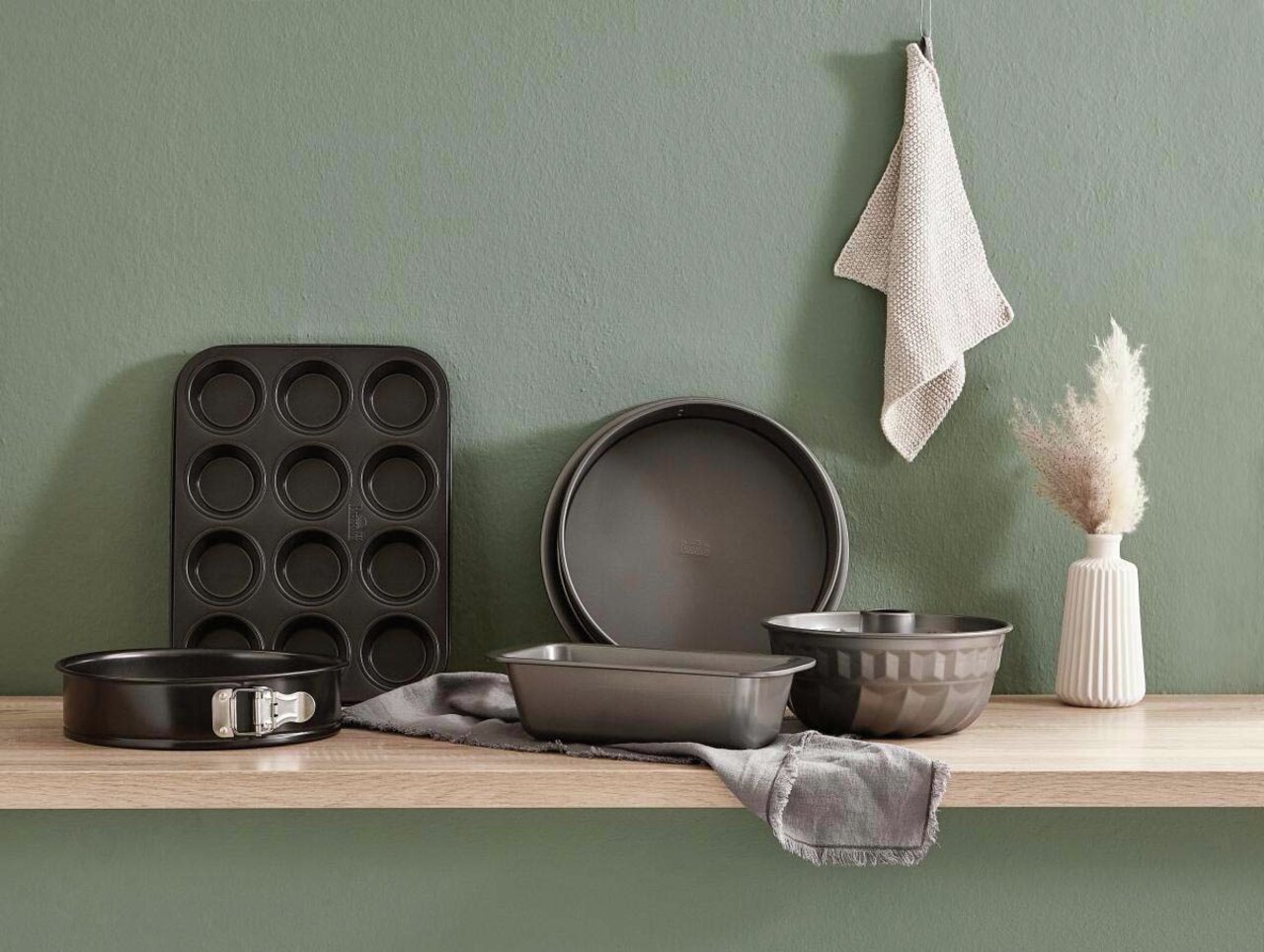 Eine Springform mit 26 cm Durchmesser, präsentiert auf einem Holzregal in einer modernen Küchenszene, umgeben von weiteren Backformen und Küchenaccessoires.