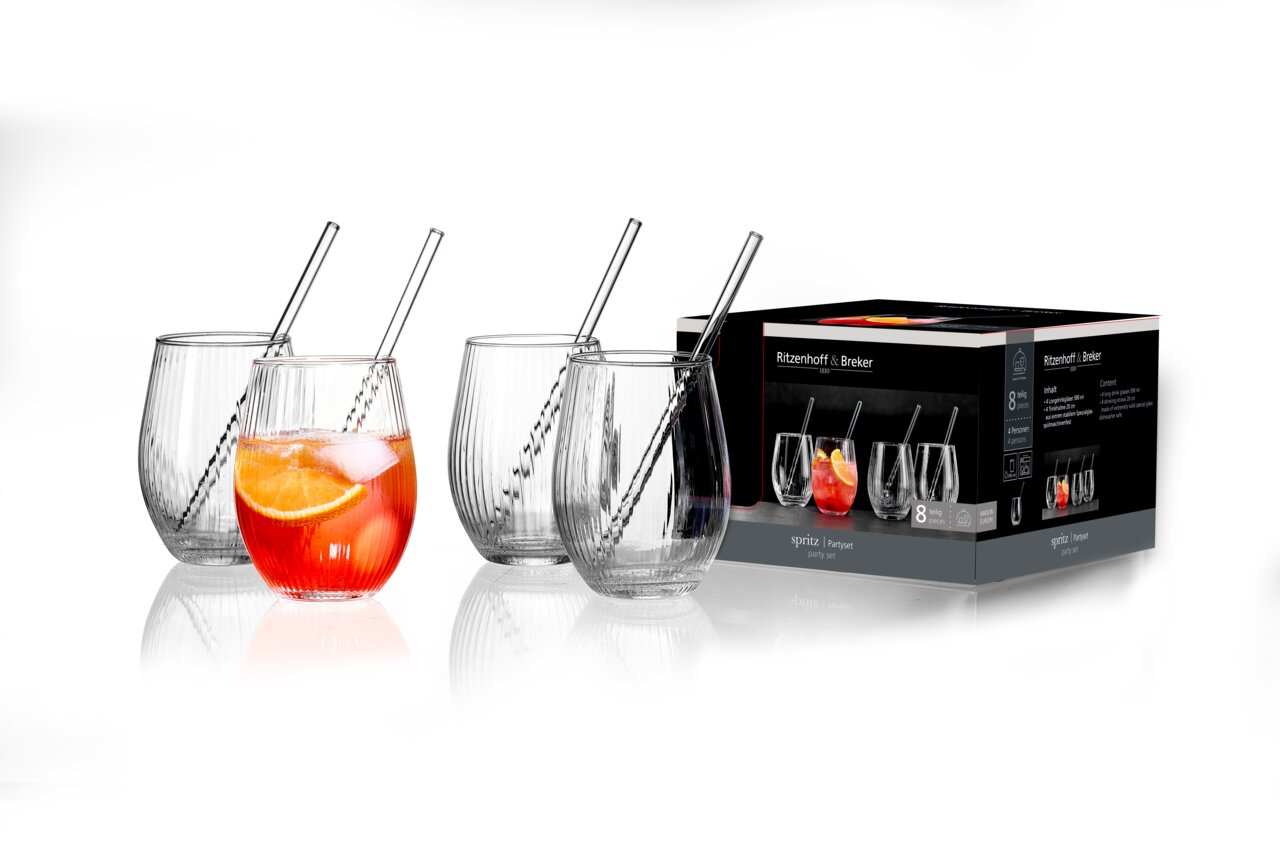 Partyset mit vier gläsernen Bechern und Trinkhalmen, eine Becher mit Getränk und Orangenscheibe, seitliche Perspektive