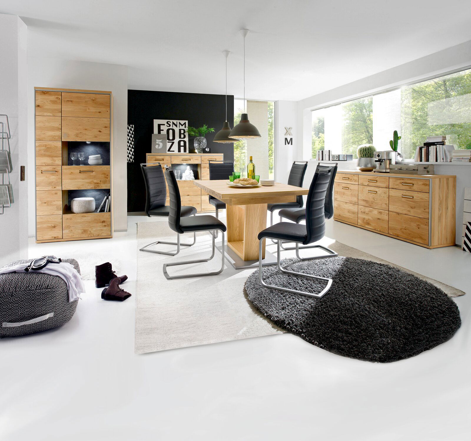 Moderner Essbereich mit einem großen Esstisch aus Holz, umgeben von schwarzen Stühlen. Der Raum ist hell und stilvoll eingerichtet, mit einem großen Fenster im Hintergrund. Perspektive: Frontalansicht auf den Esstisch.