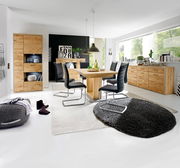 Moderner Essbereich mit einem großen Esstisch aus Holz, umgeben von schwarzen Stühlen. Der Raum ist hell und stilvoll eingerichtet, mit einem großen Fenster im Hintergrund. Perspektive: Frontalansicht auf den Esstisch.