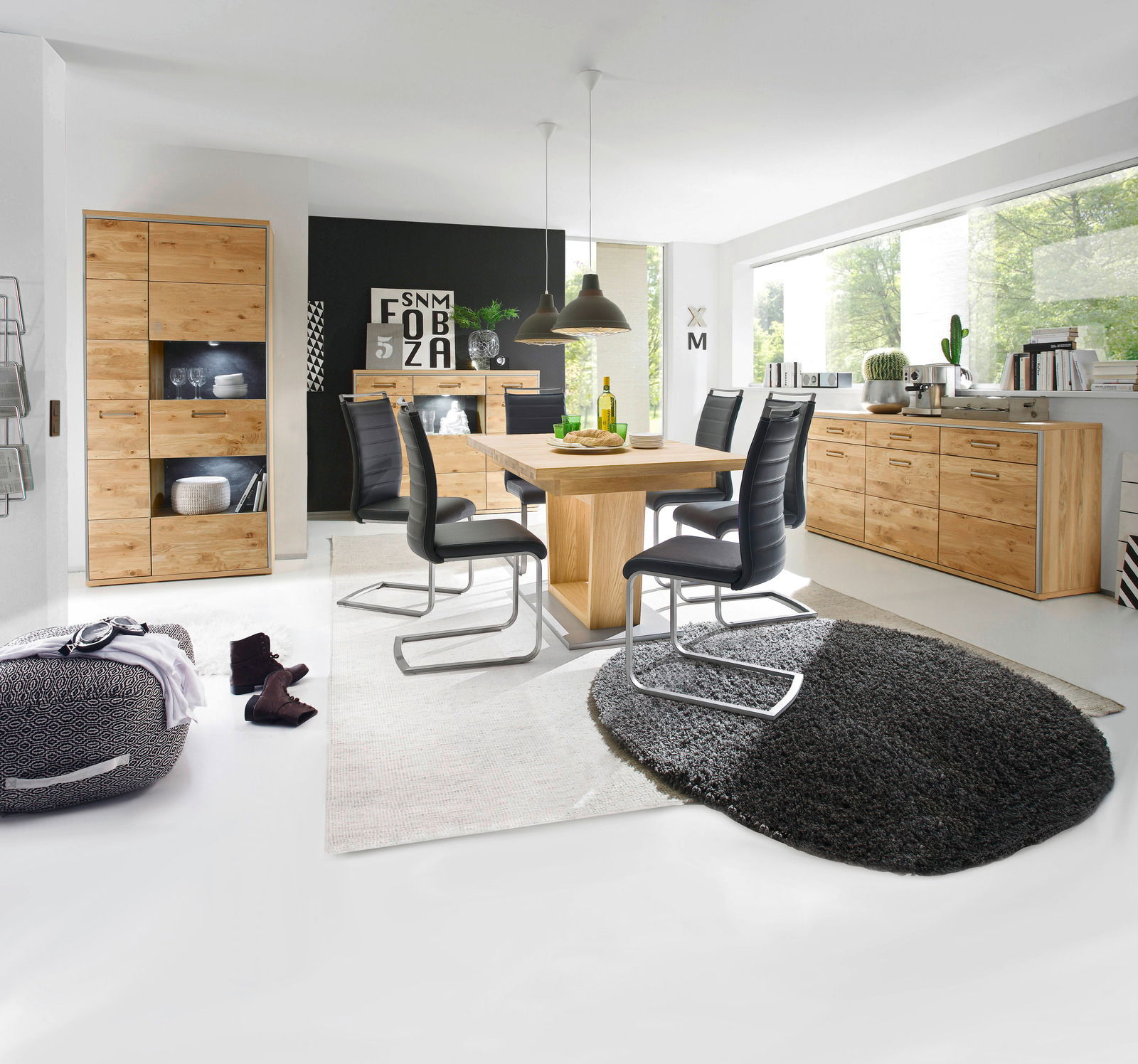 Moderner Essbereich mit einem großen Esstisch aus Holz, umgeben von schwarzen Stühlen. Der Raum ist hell und stilvoll eingerichtet, mit einem großen Fenster im Hintergrund. Perspektive: Frontalansicht auf den Esstisch.