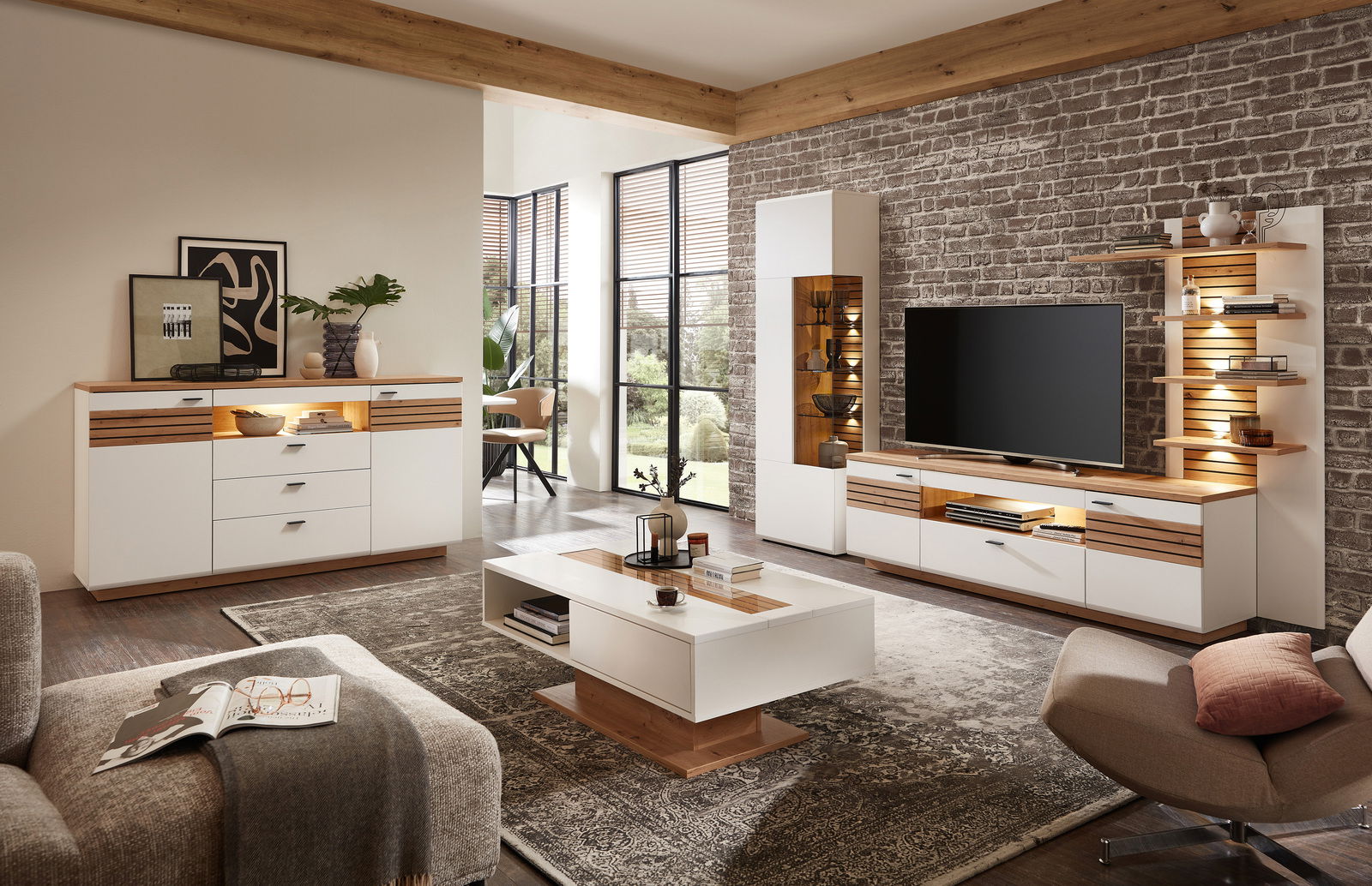 Wohnzimmeransicht mit moderner Wandkombination FRESNO, bestehend aus Sideboard, Couchtisch und TV-Möbel in Holz- und Weißtönen, mit dekorativer Beleuchtung und stilvollen Accessoires.