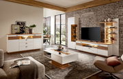 Wohnzimmeransicht mit moderner Wandkombination FRESNO, bestehend aus Sideboard, Couchtisch und TV-Möbel in Holz- und Weißtönen, mit dekorativer Beleuchtung und stilvollen Accessoires.