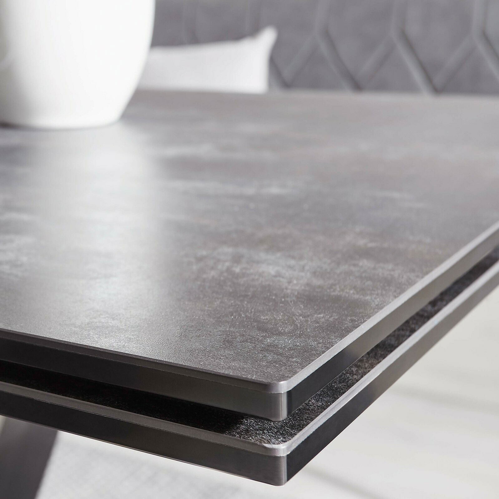 Nahaufnahme der Tischkante eines modernen Esstisches mit dunkler, glatter Oberfläche.