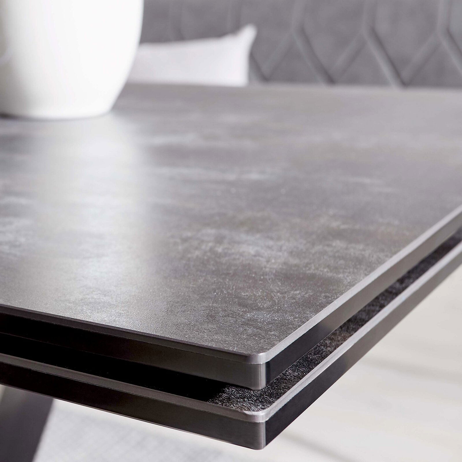 Nahaufnahme der Tischkante eines modernen Esstisches mit dunkler, glatter Oberfläche.