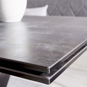 Nahaufnahme der Tischkante eines modernen Esstisches mit dunkler, glatter Oberfläche.