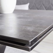 Nahaufnahme der Tischkante eines modernen Esstisches mit dunkler, glatter Oberfläche.