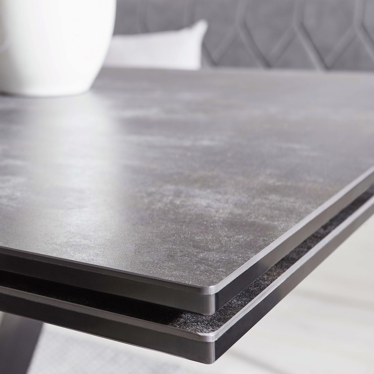 Close-up van de tafelrand van een moderne eettafel met een donker, glad oppervlak.