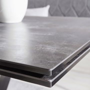 Close-up van de tafelrand van een moderne eettafel met een donker, glad oppervlak.