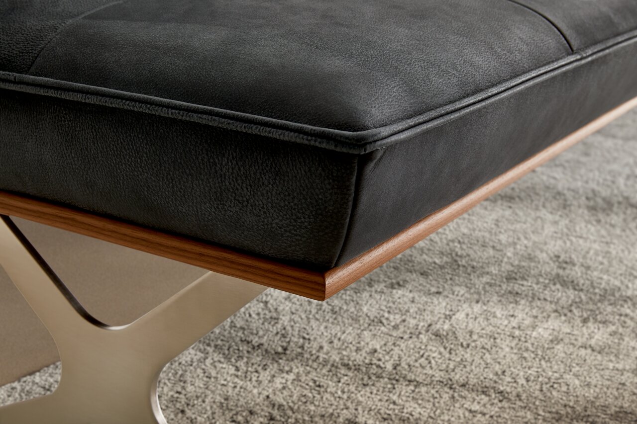 Nahaufnahme einer modernen Bank mit schwarzem Polster und Holzrahmen, seitliche Perspektive.