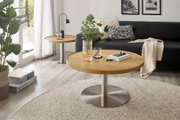 Runder Couchtisch mit Holzplatte und Metallfuß, im Wohnzimmer mit Sofa und Dekorationen, aus seitlicher Perspektive.