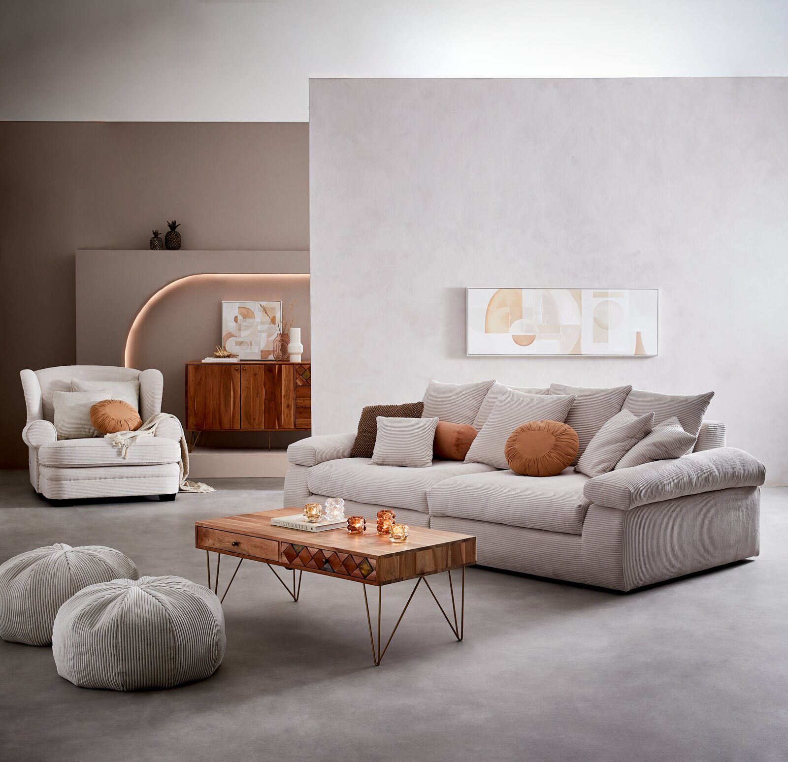 Een gezellige grote bank in een moderne woonkamer, van voren gefotografeerd, met verschillende kussens in neutrale tinten en een houten salontafel op de voorgrond.