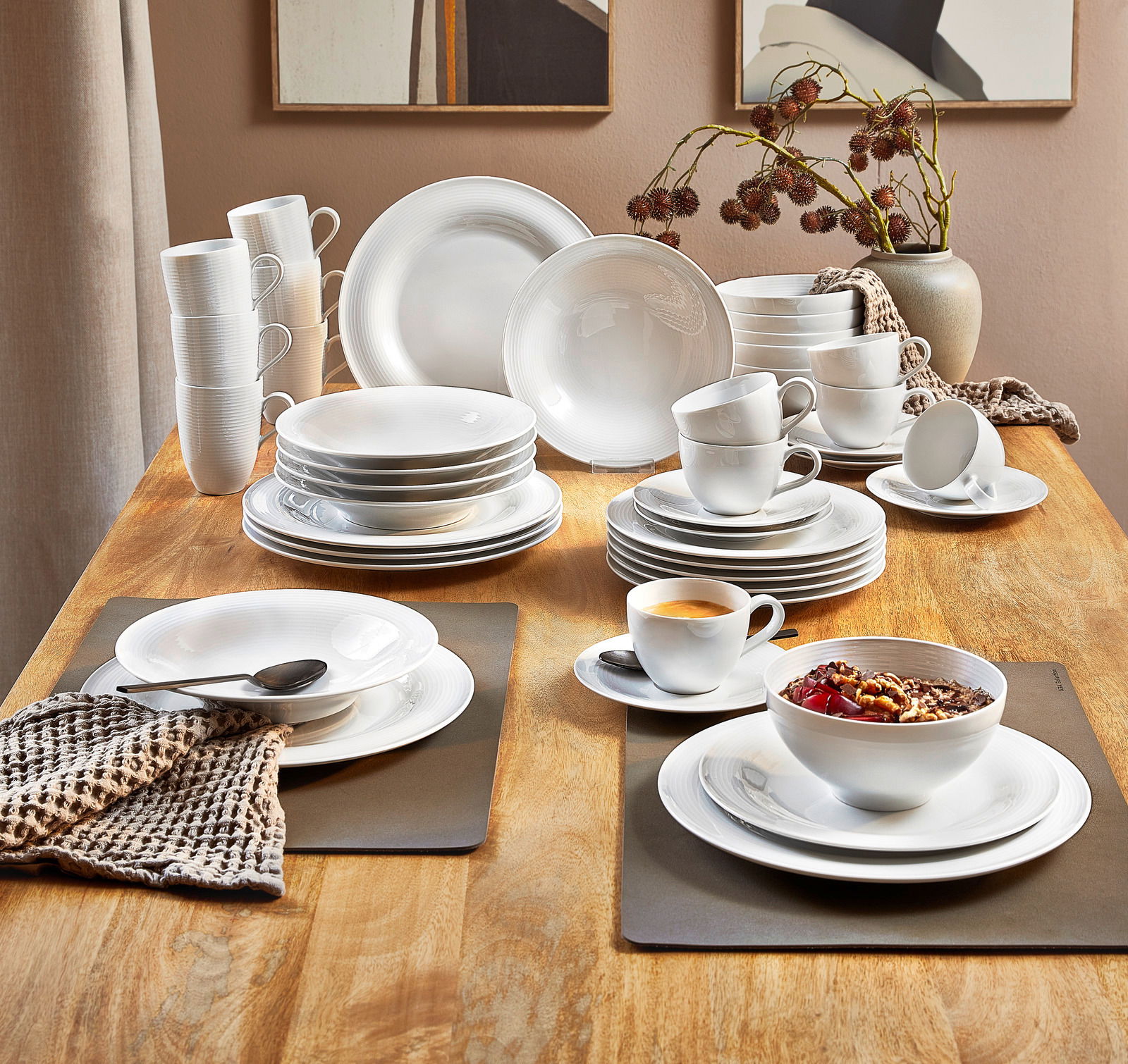 Elegantes 42-teiliges Kombiservice 'Beat' auf einem Holztisch, bestehend aus Tellern, Tassen und Schalen in moderner, weißer Optik. Perspektive von oben.