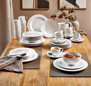 Elegantes 42-teiliges Kombiservice 'Beat' auf einem Holztisch, bestehend aus Tellern, Tassen und Schalen in moderner, weißer Optik. Perspektive von oben.