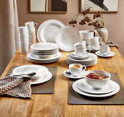 Elegantes 42-teiliges Kombiservice 'Beat' auf einem Holztisch, bestehend aus Tellern, Tassen und Schalen in moderner, weißer Optik. Perspektive von oben.