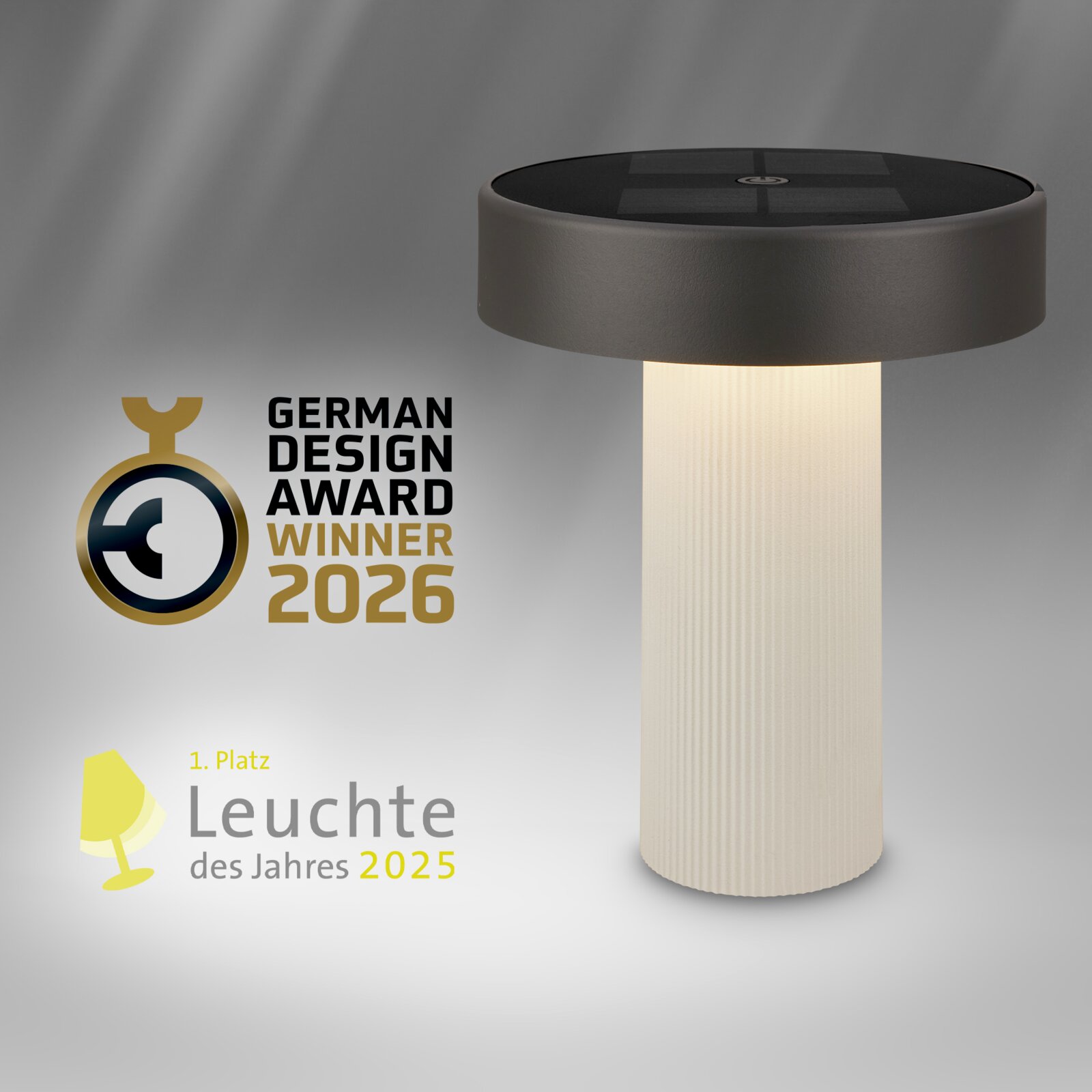 Moderne Tischleuchte mit zylindrischem, warmweiß leuchtendem Sockel und schwarzem, scheibenförmigem Kopf mit Solarzellen; Produktansicht schräg von vorn/leicht von oben, daneben Auszeichnungen „German Design Award Winner 2026“ und „Leuchte des Jahres 2025