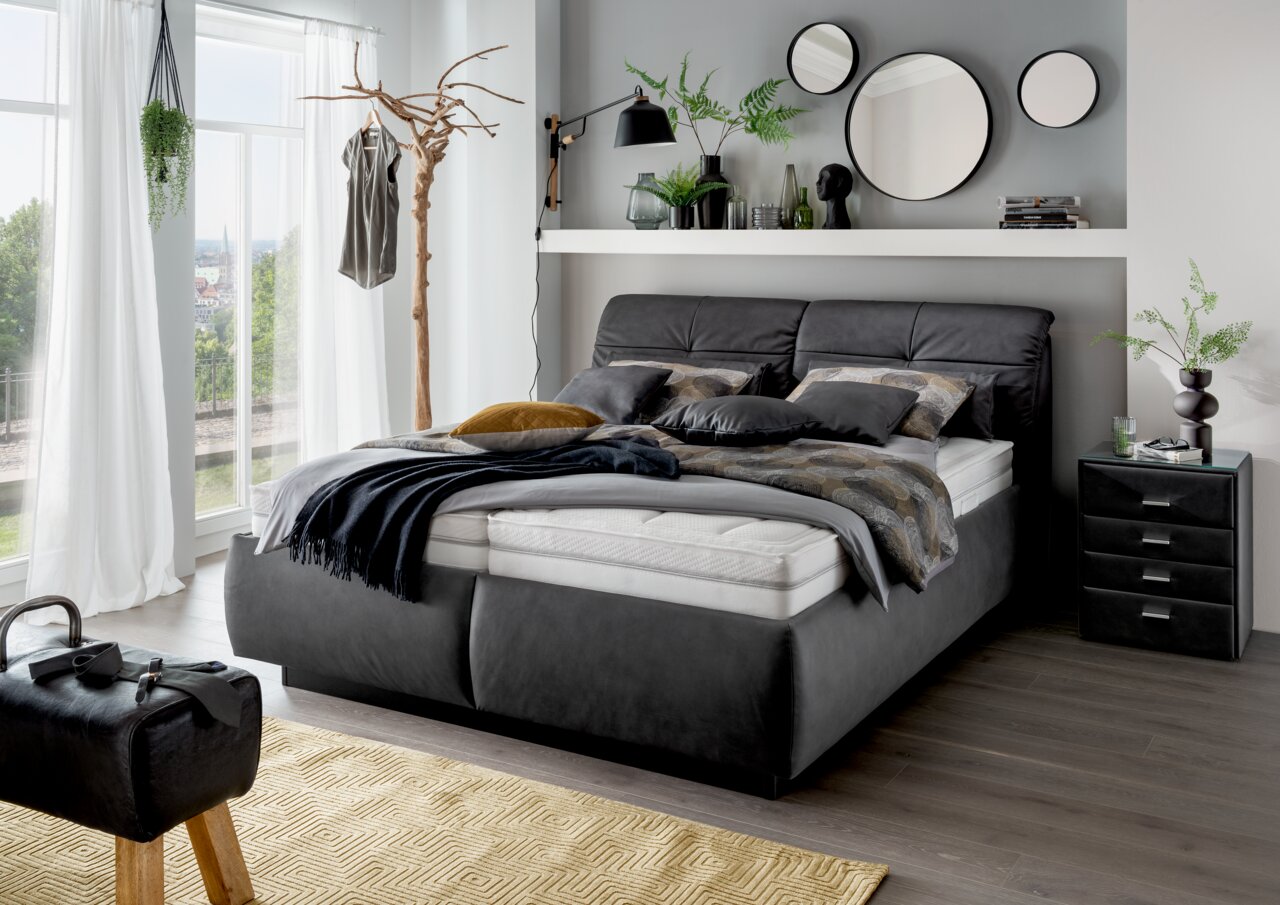Modernes Polsterbett in einem stilvoll eingerichteten Schlafzimmer, seitliche Perspektive.