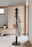 Umbra Garderobenständer FLAPPER Moderner schwarzer Garderobenständer mit mehreren Haken, auf denen ein Mantel und eine Tasche hängen, in einem hellen Raum mit Holzfußboden und minimalistischer Einrichtung. Seitliche Perspektive.