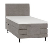 Lichtgrijs gestoffeerd boxspringbed met hoog hoofdbord, witte topper en zwarte poten, schuin van voren gezien