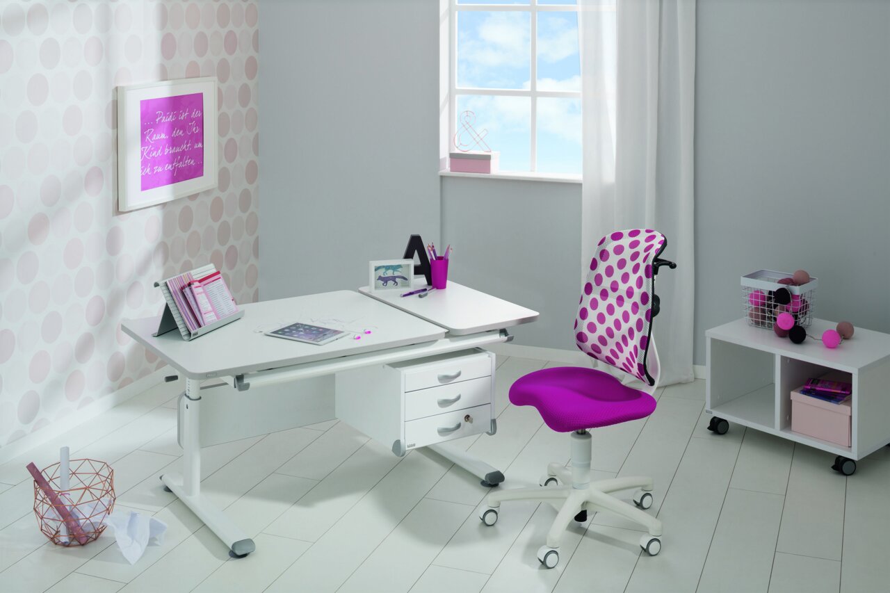 Moderner Schreibtisch in einem hellen Raum mit einem ergonomischen Stuhl in Pink und Weiß, seitliche Perspektive.