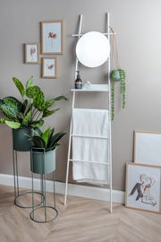 Ein modernes Pflanzgefäß-Set bestehend aus drei Teilen, präsentiert in einem stilvollen Innenraum. Zwei Pflanzen stehen in eleganten, grünen Töpfen auf Metallständern. Perspektive: Frontalansicht.