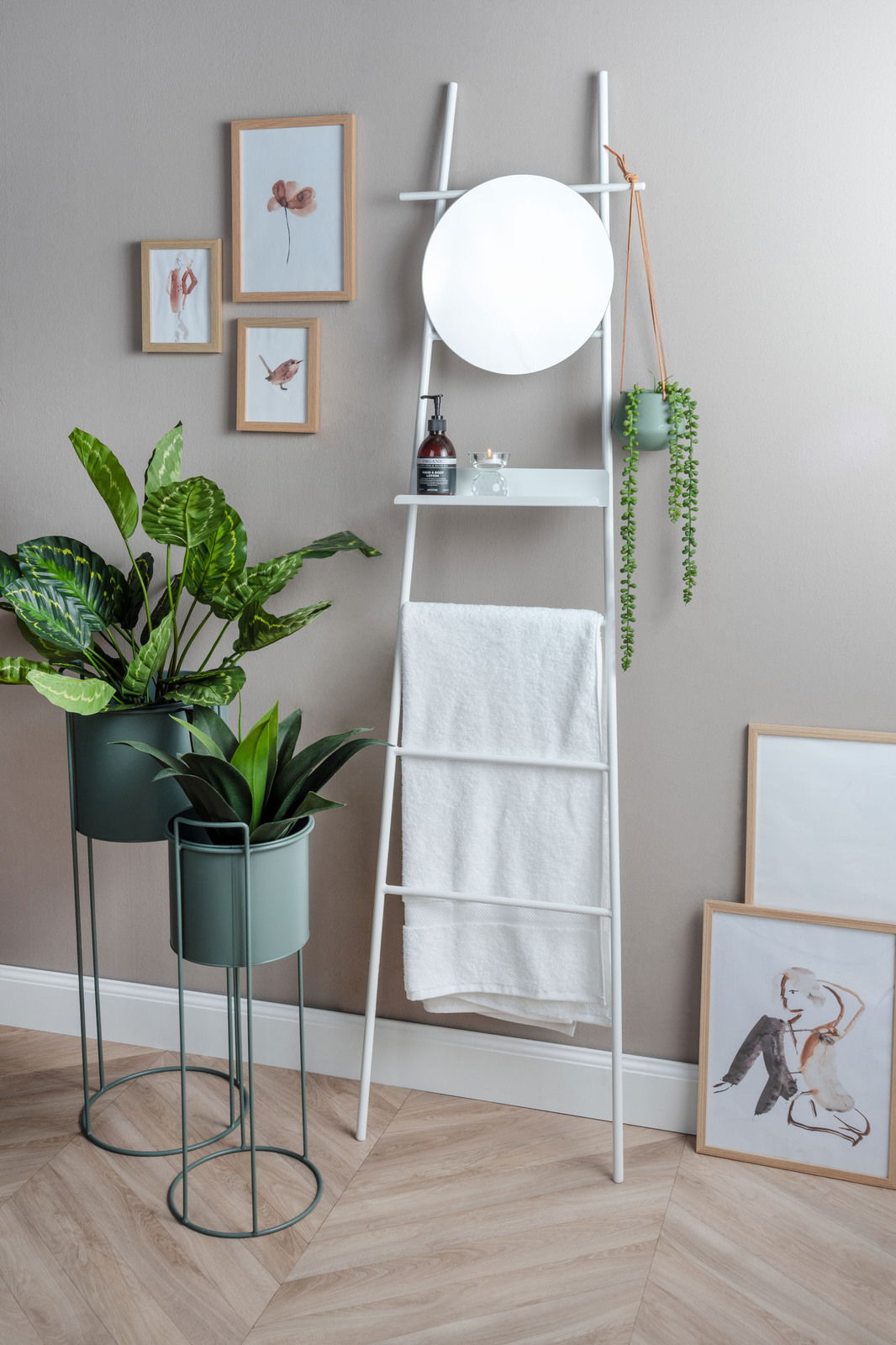 Ein modernes Pflanzgefäß-Set bestehend aus drei Teilen, präsentiert in einem stilvollen Innenraum. Zwei Pflanzen stehen in eleganten, grünen Töpfen auf Metallständern. Perspektive: Frontalansicht.