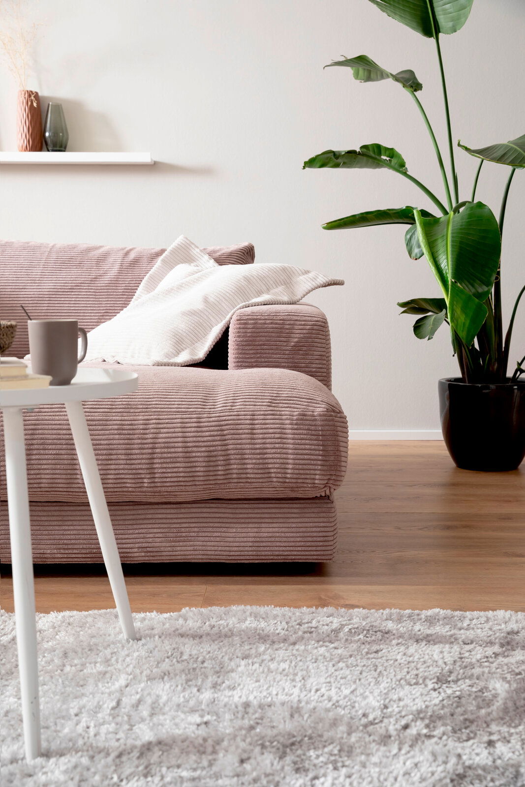 Großes Megasofa in einem modernen Wohnzimmer, seitliche Perspektive mit Kissen, Beistelltisch und Zimmerpflanze.