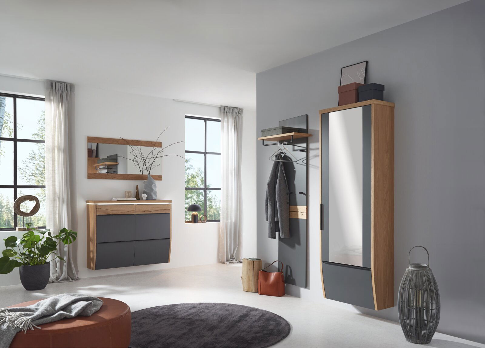 Modernes Flur-Set in Eiche und Anthrazit mit Garderobenpaneel, Spiegel, Hängeschrank und Kommode, gezeigt in schräger Frontansicht im hellen Eingangsbereich
