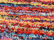 Nahaufnahme eines bunten, flauschigen Teppichs mit verschiedenen Farben wie Rot, Blau, Gelb und Lila, aus einer schrägen Perspektive fotografiert.