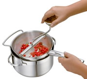 Passiergerät aus Edelstahl in der Seitenansicht, das rote Beeren in einem Topf passiert.