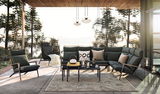 Moderne Loungegarnitur mit dunkelgrünen Polstern und eleganten Metallrahmen, umgeben von einem natürlichen Außenbereich mit Seeblick, aus der Frontalperspektive.