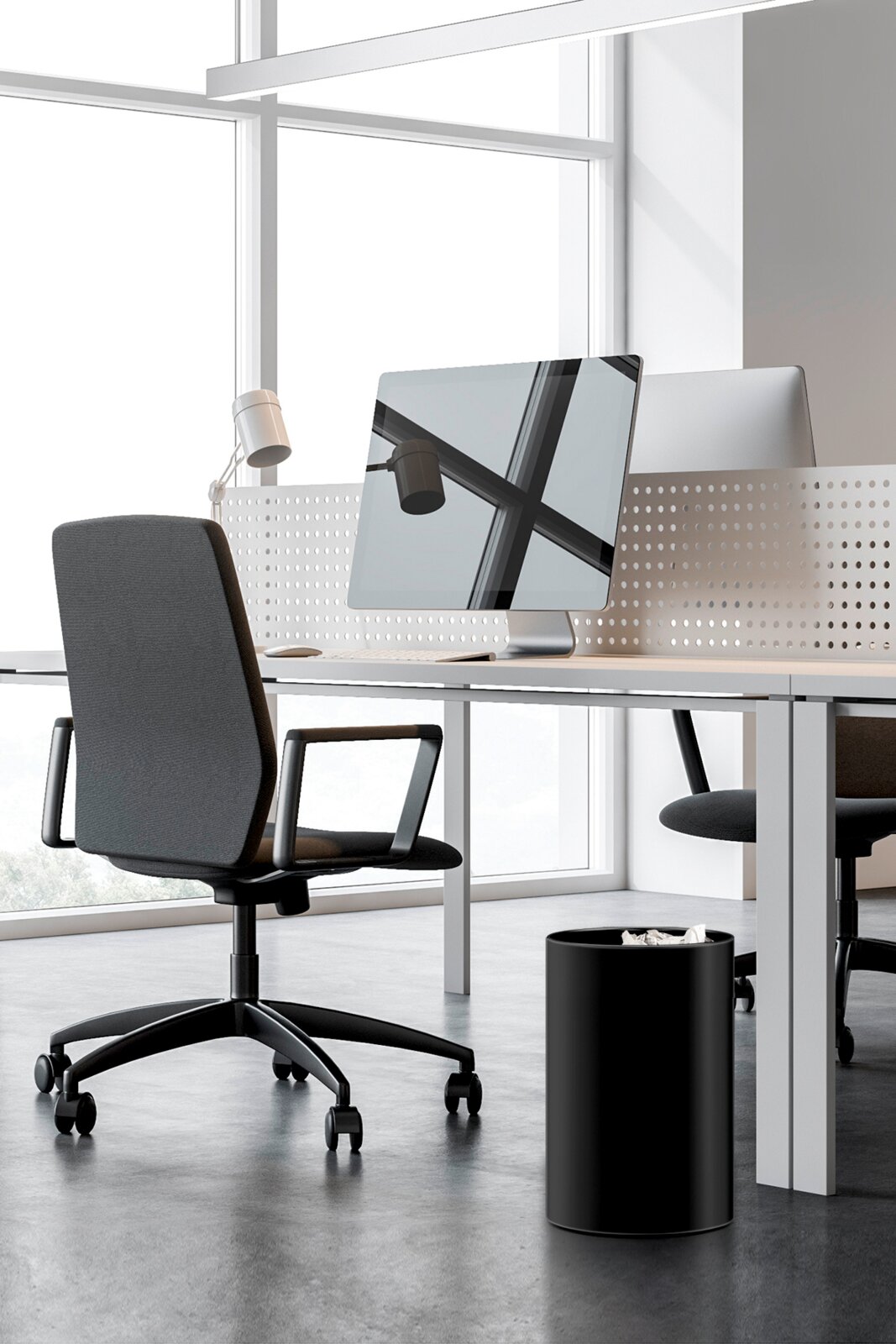 Schwarzer zylindrischer Papierkorb aus Metall unter einem modernen Schreibtisch im Büro, aufgenommen in seitlicher 3/4-Perspektive auf Bodenhöhe