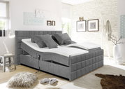 Modernes graues Polsterbett mit verstellbaren Matratzen, seitlicher Perspektive, in einem stilvoll eingerichteten Schlafzimmer.