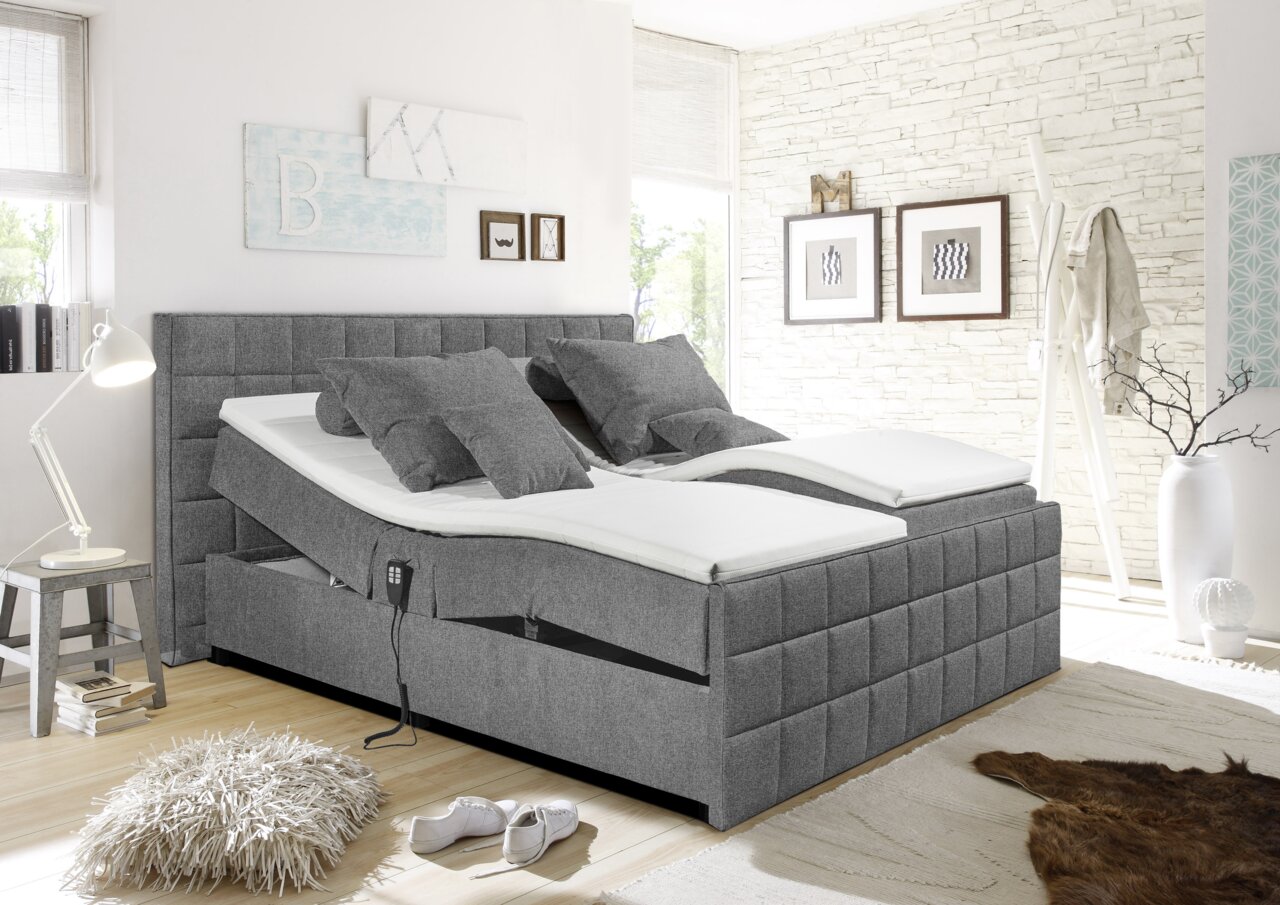 Modernes graues Polsterbett mit verstellbaren Matratzen, seitlicher Perspektive, in einem stilvoll eingerichteten Schlafzimmer.