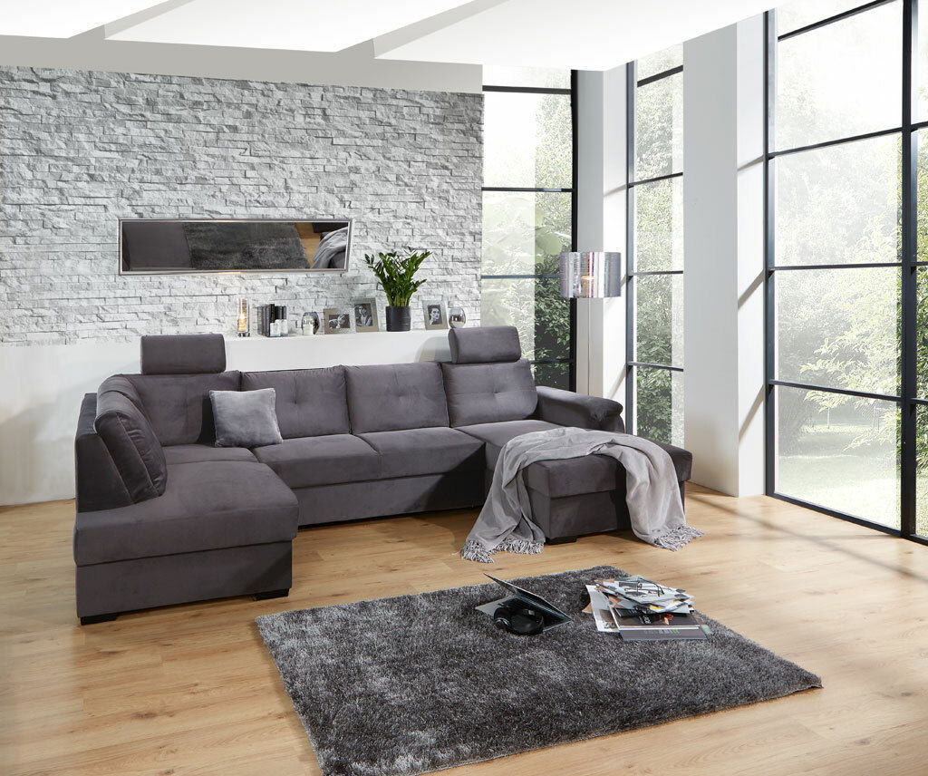 Graues Ecksofa in modernem Wohnzimmer mit großen Fenstern, von vorne betrachtet.