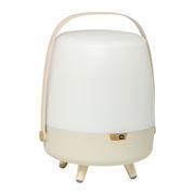 Tragbare Lampe mit integriertem JBL-Lautsprecher, sandfarben, auf drei Beinen stehend, mit Tragegriff, Frontalansicht.