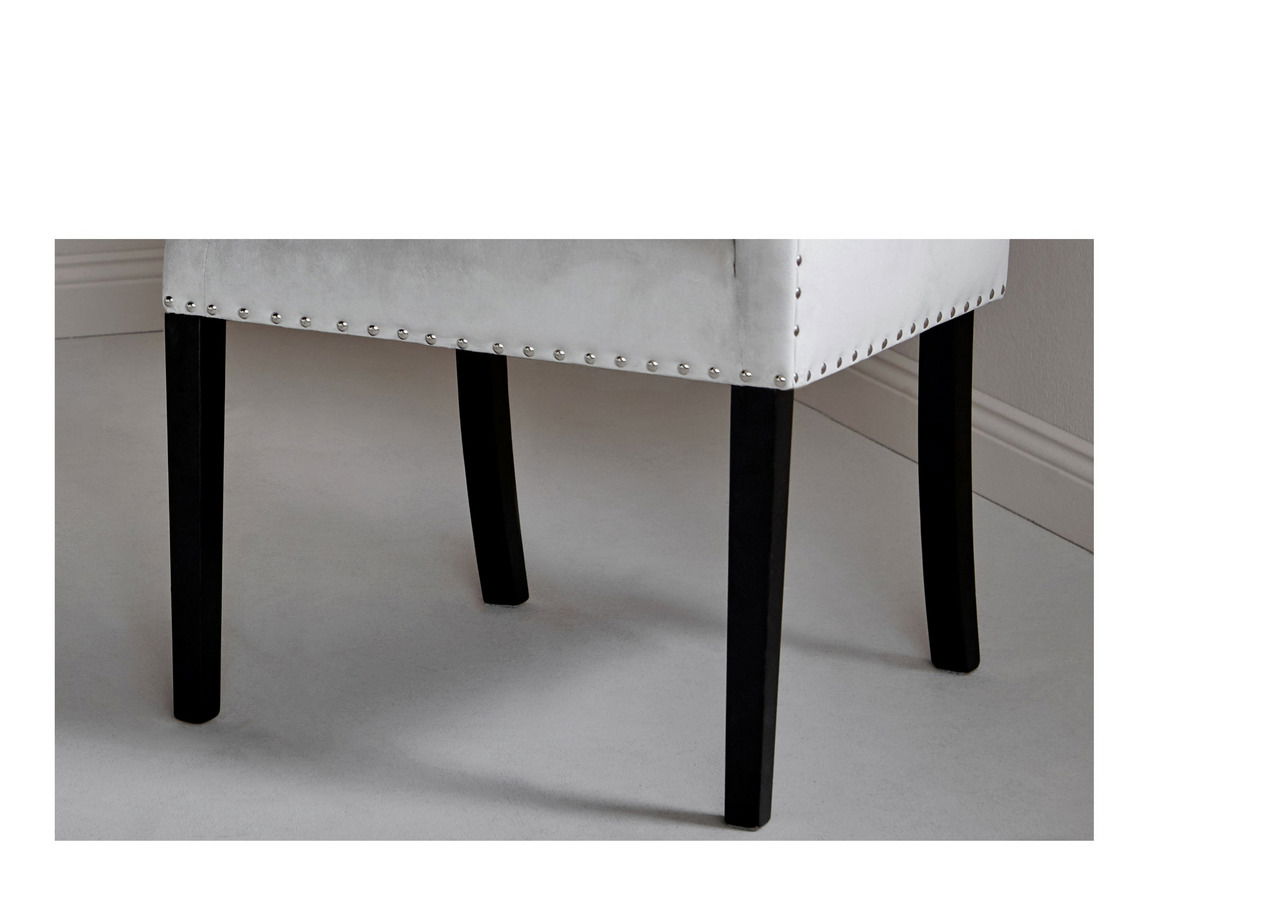 Nahaufnahme eines Stuhls mit schwarzem Holzbein und heller Polsterung, seitliche Perspektive