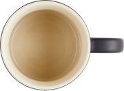 Cremefarbene Tasse mit dunklem Rand und schwarzem Henkel, in direkter Draufsicht vor weißem Hintergrund