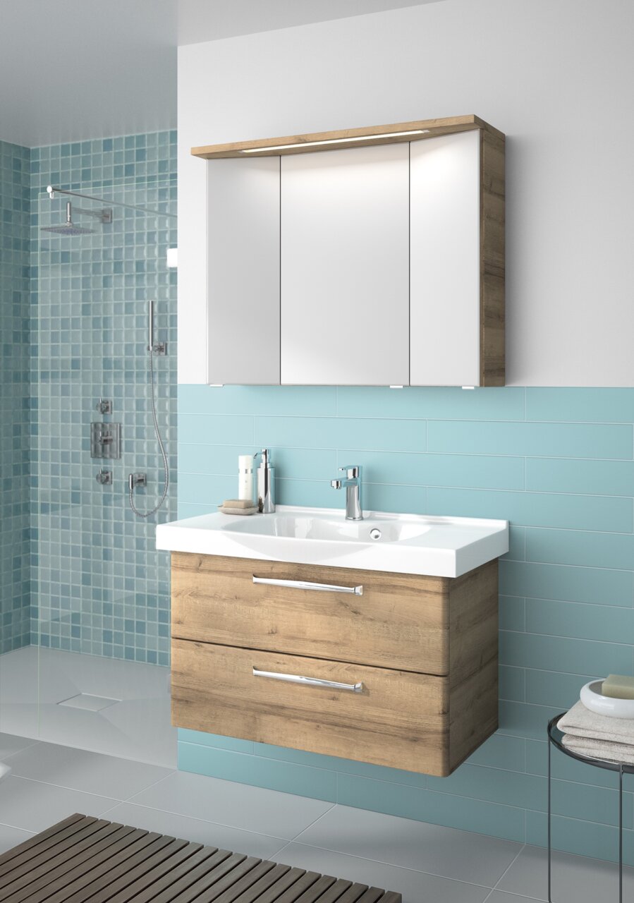 Modern badkamermeubel met houtlook en een witte wastafel, gezien vanaf de voorkant, in een badkamer met blauwe tegels.