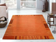 Wollteppich in warmen Orangetönen mit geometrischem Muster, in einem modernen Wohnzimmer auf hellem Holzboden aus der Vogelperspektive fotografiert.