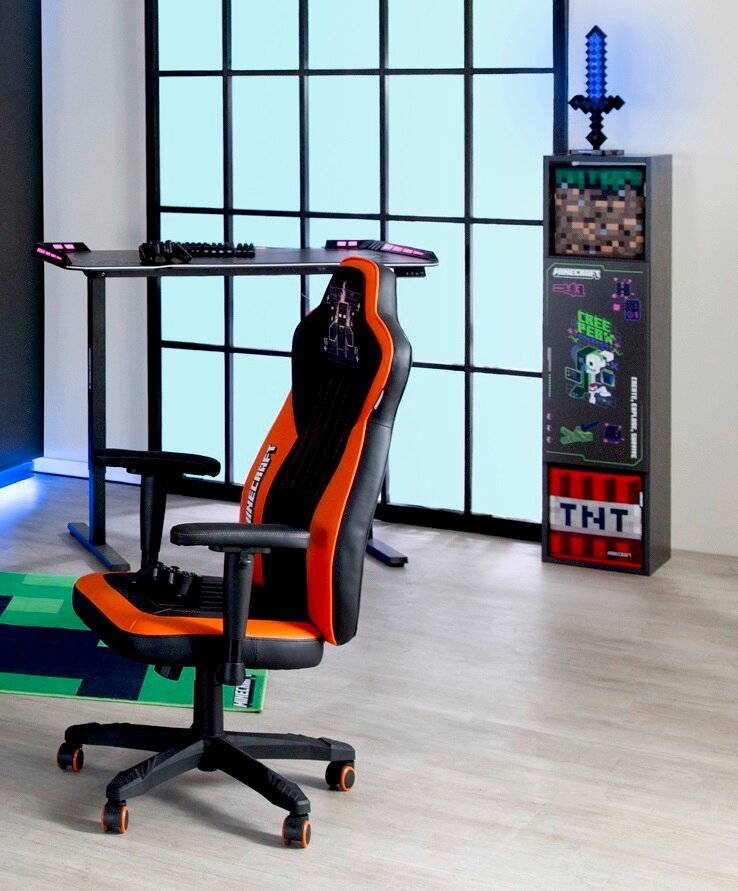 Zurbrüggen Bank/rek (vitrine) MINECRAFT Gamingstoel in oranje en zwart, gezien vanaf de zijkant, naast een bureau en een boekenkast met Minecraft-motieven.